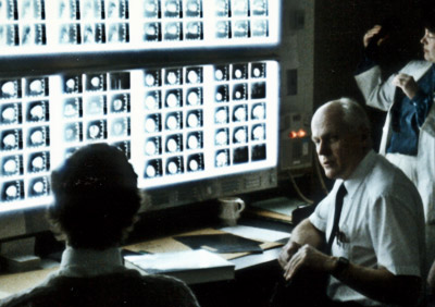 Photo of Atis K. Freimanis, M.D. speaking to student in front of computer monitor